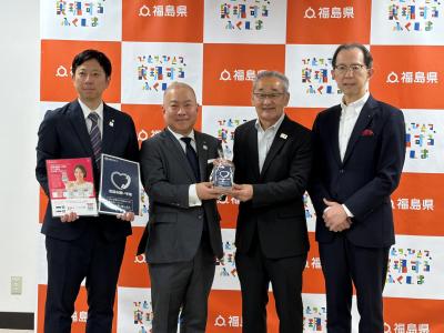 電話お願い手帳を持って微笑むＮＴＴ東日本福島支店川辺企画総務部長、大橋支店長、吉田会長、内堀知事